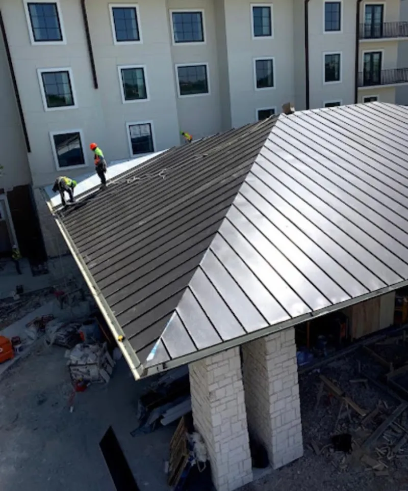 Crew installing standing seam metal roof panels on a commercial project in Papillion